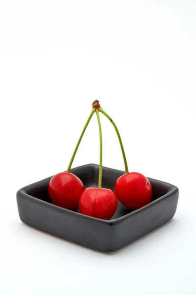 Three cherries in a black bowl — Stock Photo, Image