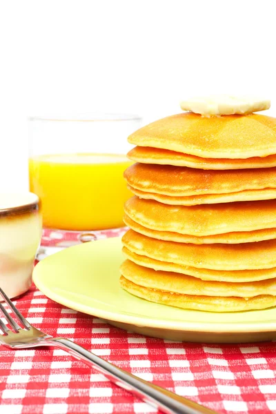 Een grote stapel van pannenkoeken met boter en sinaasappelsap op witte achtergrond. s — Stockfoto