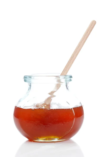 Μέλι στη γυάλινη επιφάνεια βάζο απομονωθεί σε λευκό φόντο. ρηχό βάθος πεδίου — Φωτογραφία Αρχείου