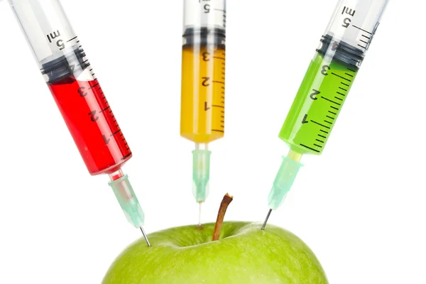 Green apple with three syringes inserted — Stock Photo, Image