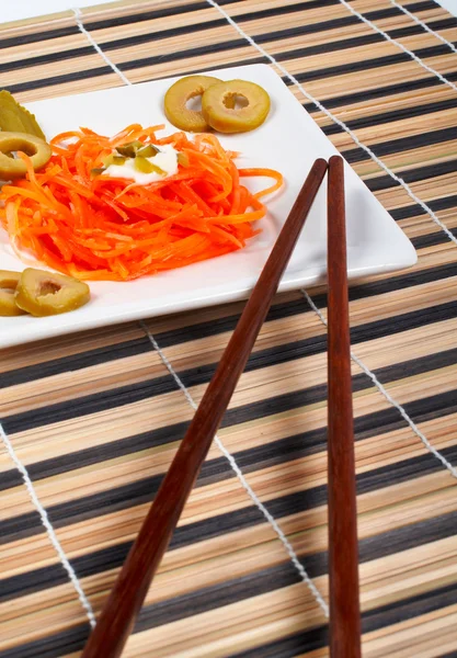 Салат з моркви на порцеляновій тарілці з паличками — стокове фото
