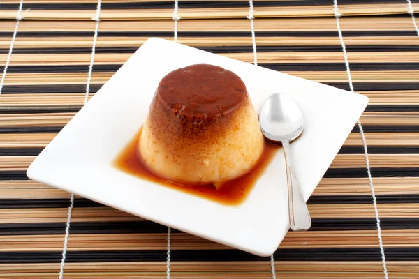 Vanillecreme und Karamell-Dessert mit Löffel auf weißem Teller — Stockfoto