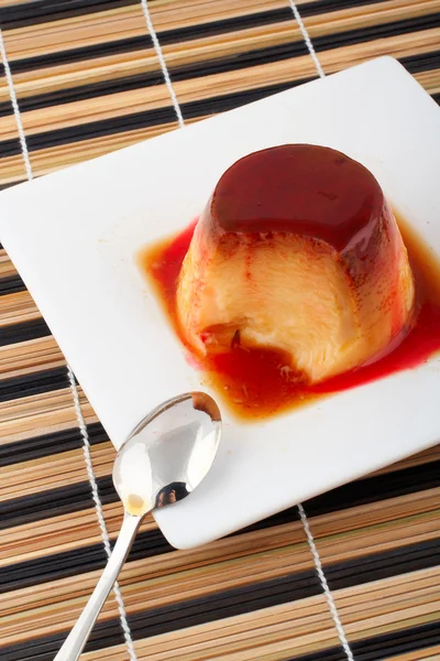 Creme de baunilha e sobremesa de caramelo com colher em prato branco — Fotografia de Stock
