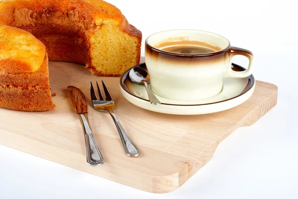 Bolo de esponja com a xícara de café, colher, faca e garfo em placa de madeira — Fotografia de Stock