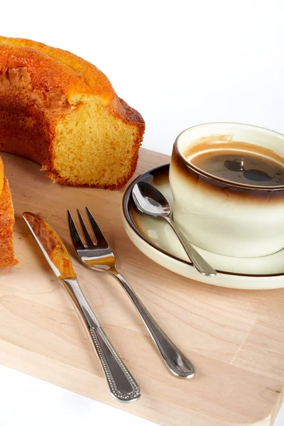 Sponge cake with the cup of coffee, spoon, knife and fork on wood plate — Stock Photo, Image