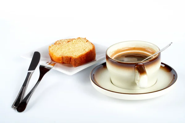 Biskuitkuchen mit der Tasse Kaffee, Löffel, Messer und Gabel auf weißer Keramik — Stockfoto