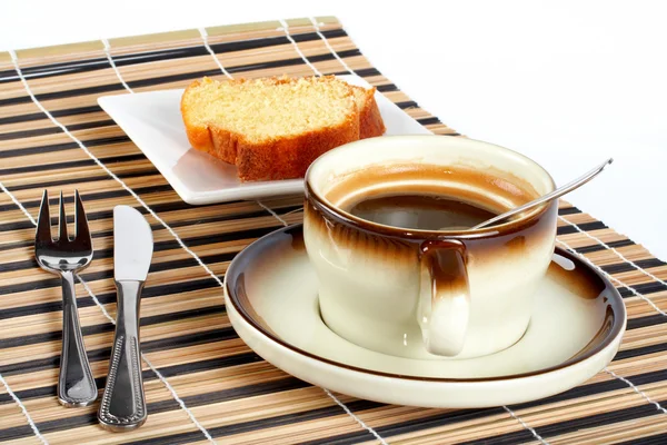 Παντεσπάνι με το κουτάλι μέσα φλιτζάνι καφέ, μαχαίρι και πιρούνι — Φωτογραφία Αρχείου