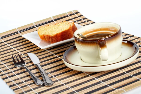 Sponge cake with the spoon inside cup of coffee, knife and fork — Stock Photo, Image