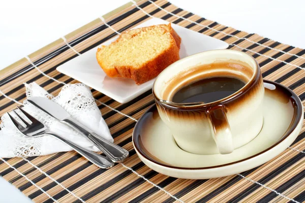 Sponge cake with the spoon inside cup of coffee, knife and fork — Stock Photo, Image