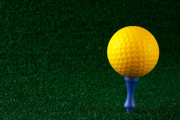Yellow golfball and blue tee — Stock Photo, Image
