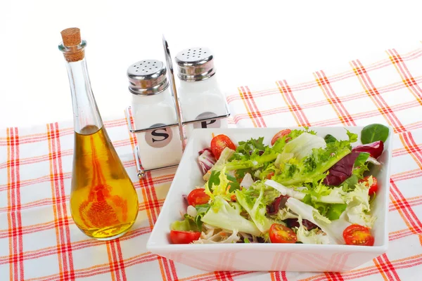 Oil bottle, green salad, salt and pepper — Stock Photo, Image