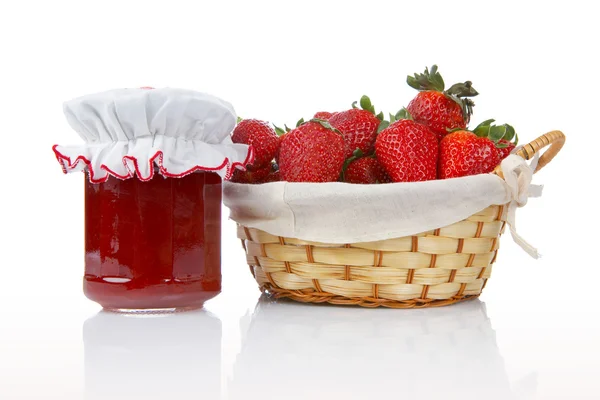 Jam jar and basket of strawberries — Stock Photo, Image