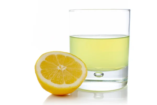 Половина и стакан свежего лимонного сока — стоковое фото
