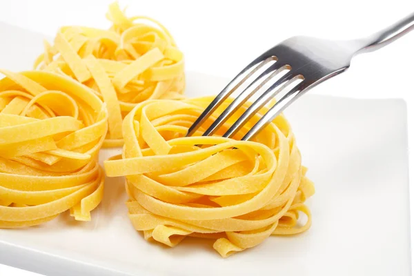 Uncooked pasta nests and fork — Stock Photo, Image