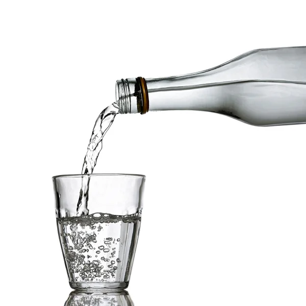 Water is gegoten uit de fles aan het glas — Stockfoto