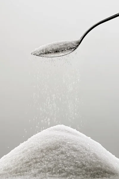 Hög av socker och en sked Stockbild