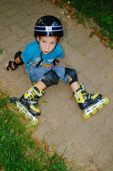 De jongen viel rolschaatsen — Stockfoto