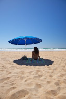 Blue parasol with woman sit on towel clipart