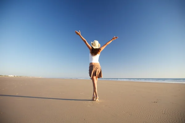 Mujer feliz con sombrero caminando en la playa — Foto de Stock