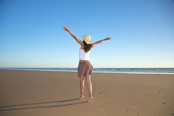 Szczęśliwa kobieta kapeluszu spaceru na plaży — Zdjęcie stockowe