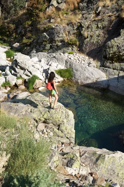 Vrouw op een rots kijken rivier — Stockfoto