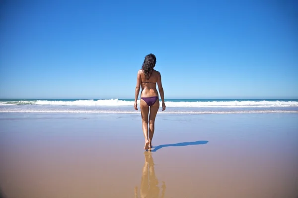Mulher caminhando em direção à água na praia — Fotografia de Stock