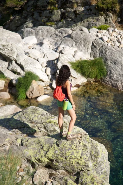 Trekking mulher em um rio de observação de rocha — Fotografia de Stock