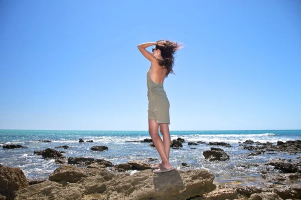 Mulher bonita andando sobre rochas próximo oceano — Fotografia de Stock