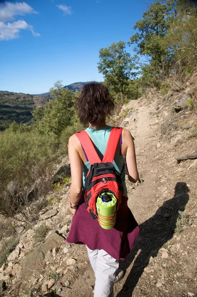 Sac à dos rouge femme marchant dans la montagne — Photo