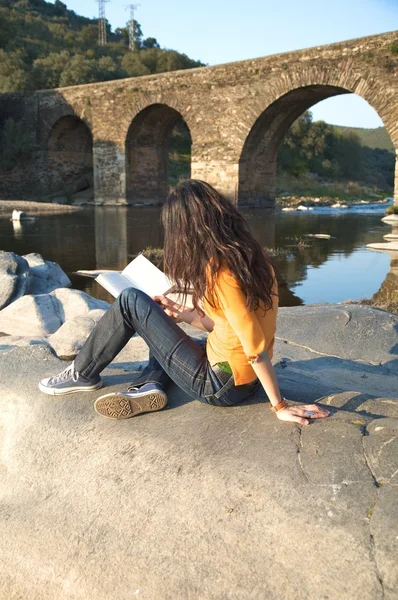 Reading next to a river — Stock Photo, Image
