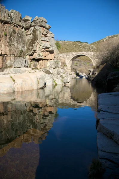 Река со скалой и мостом — стоковое фото