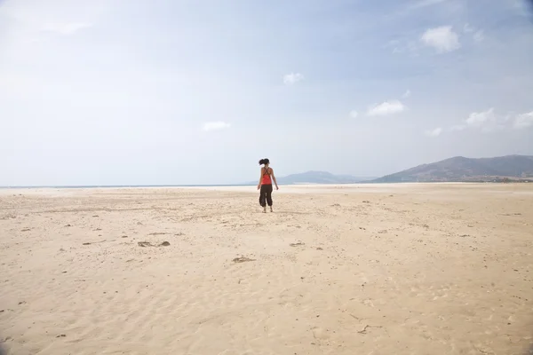 Vrouw aan het strand lances terug — Stockfoto