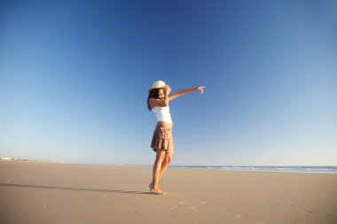 Pointing woman with hat at beach clipart