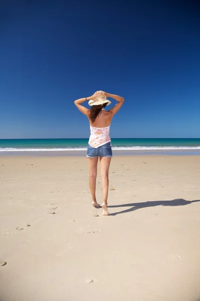 Sujetando sombrero de paja en la playa — Foto de Stock