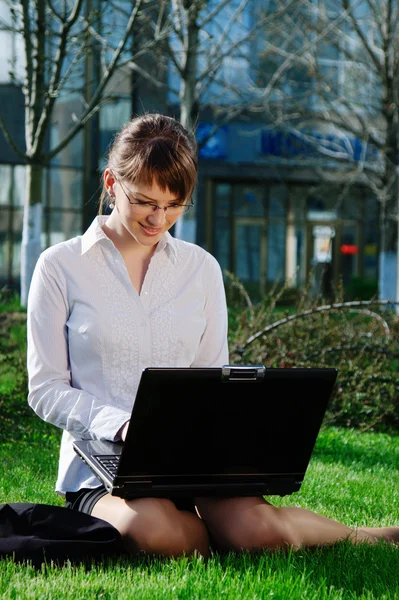 Vrouw liggen op gras met laptop — Stockfoto