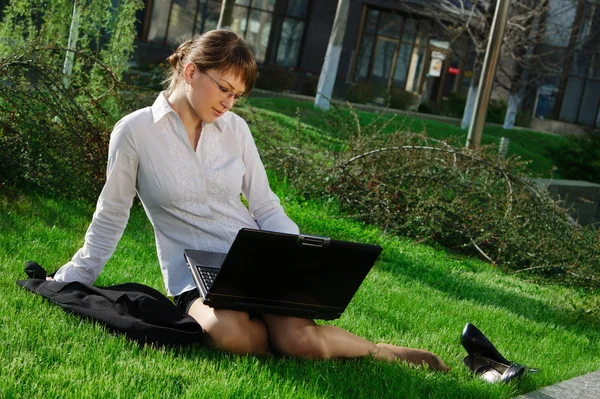 Жінка лежить на траві з ноутбуком — стокове фото