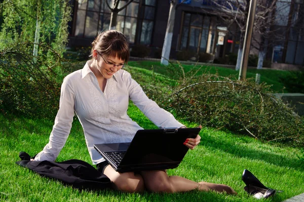 Žena leží na trávě s notebookem — Stock fotografie