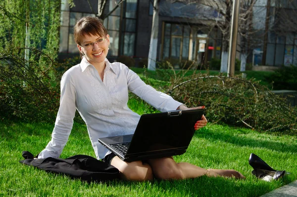 Жінка лежить на траві з ноутбуком — стокове фото