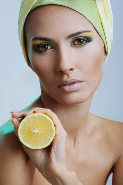 Beautiful woman with lemon in yellow scarf — Stock Photo, Image