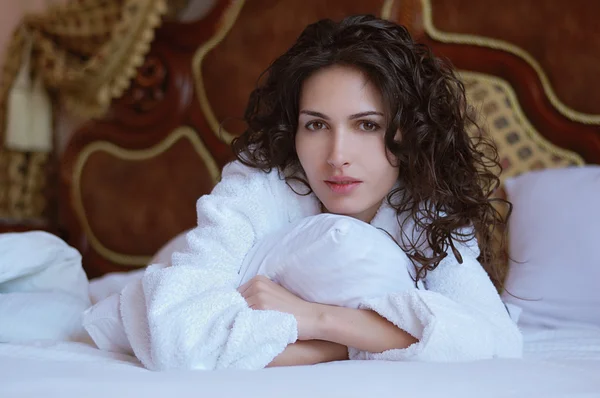 Belle femme couchée sur un lit dans un peignoir blanc — Photo