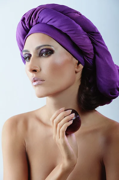 Mulher bonita com ameixa em cachecol violeta na cabeça e maquiagem brilhante — Fotografia de Stock