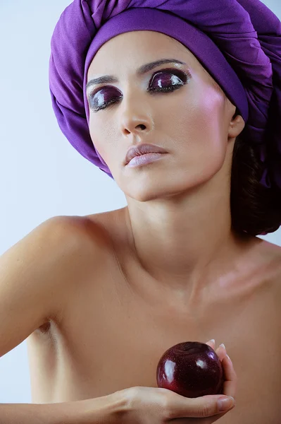 Beautiful woman with plum in violet scarf on her head and closed eyes — Stock Photo, Image
