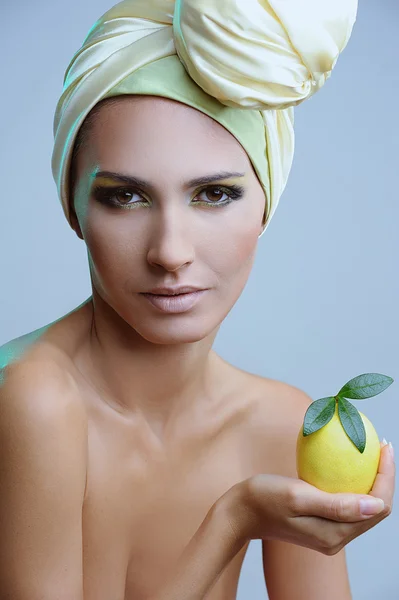 Hermosa mujer con bufanda amarilla en la cabeza y limón en la mano — Foto de Stock