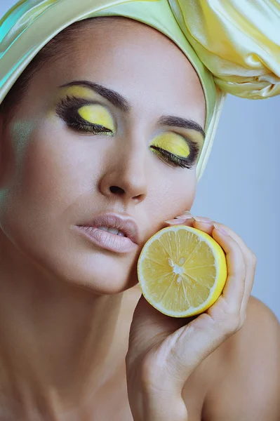 Beautiful woman with lemon in yellow scarf on her head and closed eyes — Stock Photo, Image