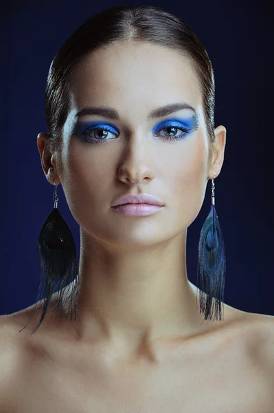 Beautiful girl with blue make-up in long earrings — Stock Photo, Image