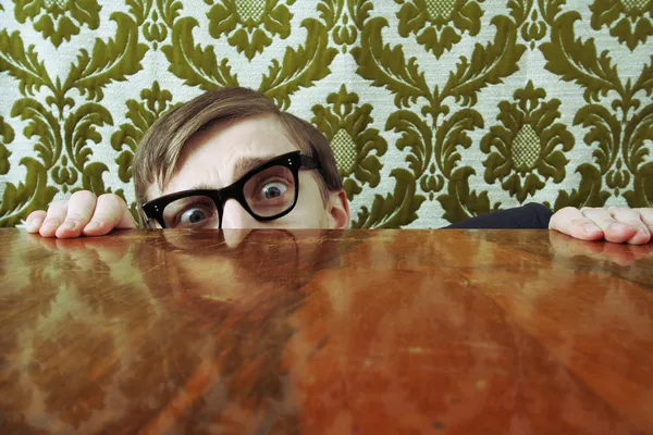 Grappige nerd verbergen achter een bureau — Stockfoto