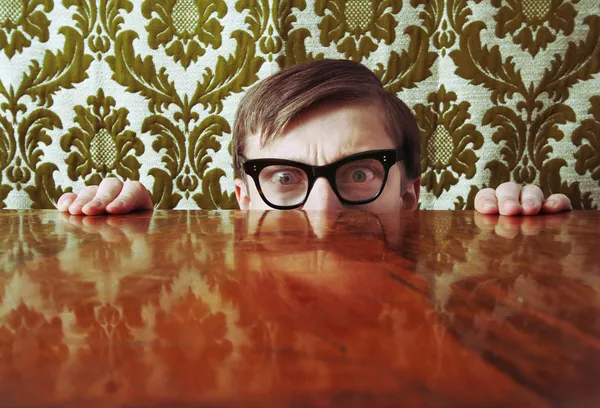 Bang nerd hidding achter een bureau — Stockfoto