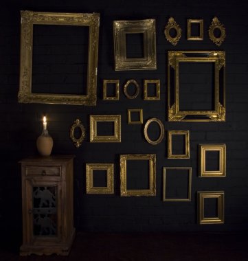 Gold frames on a black brick wall and candle clipart