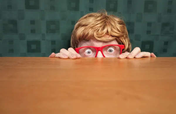 Verängstigter Nerd versteckt sich hinter Schreibtisch — Stockfoto