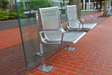 Stainless steel chairs at a bus stop. clipart